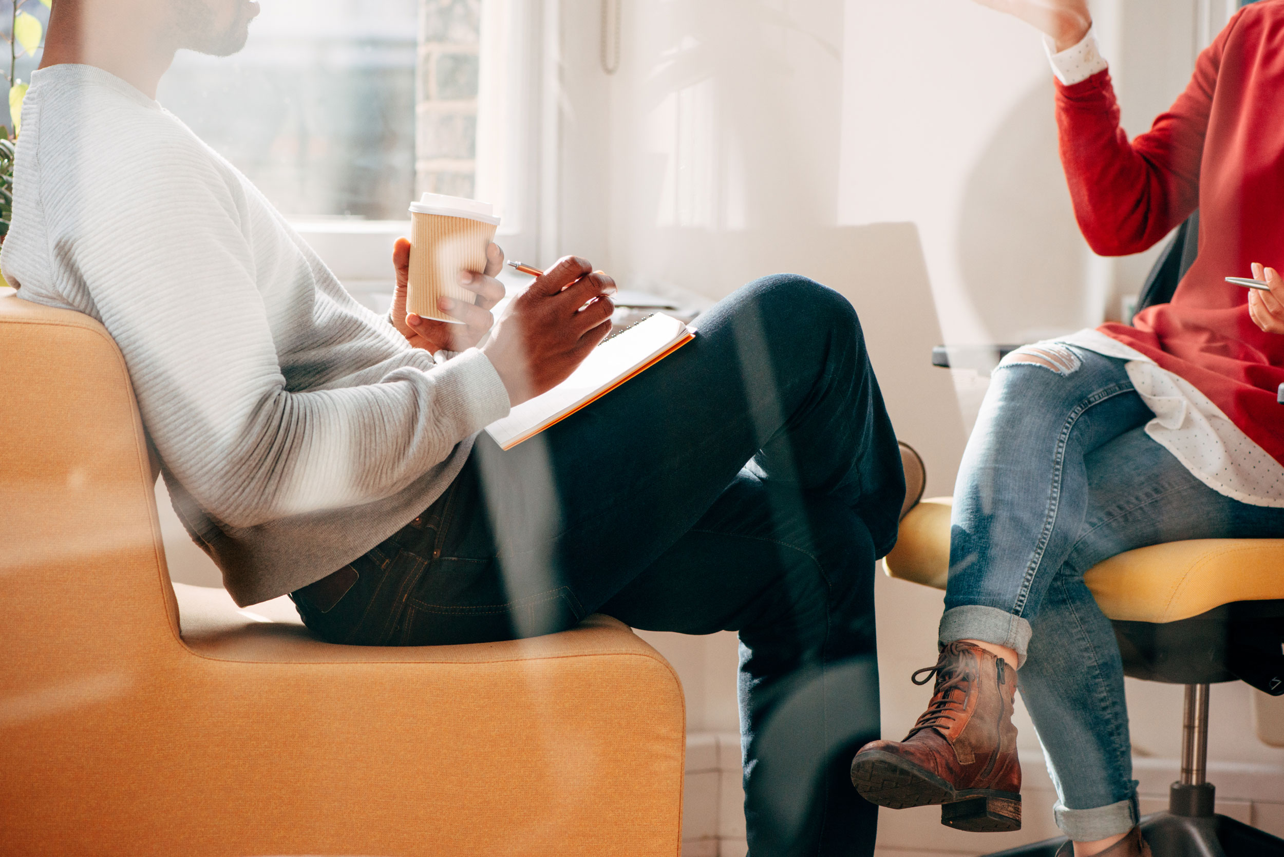 Två personer i samtal med anteckningar och kaffe